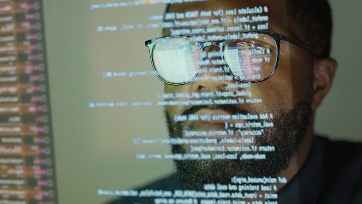 Man studying a see-through display depicting Python computer coding.